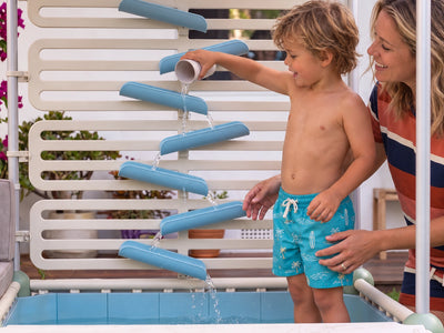 Child pouring water down The Lagoon water chutes with a parent beside them